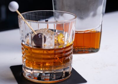 ParT Barn glass of alcohol with a golf ball themed stir stick